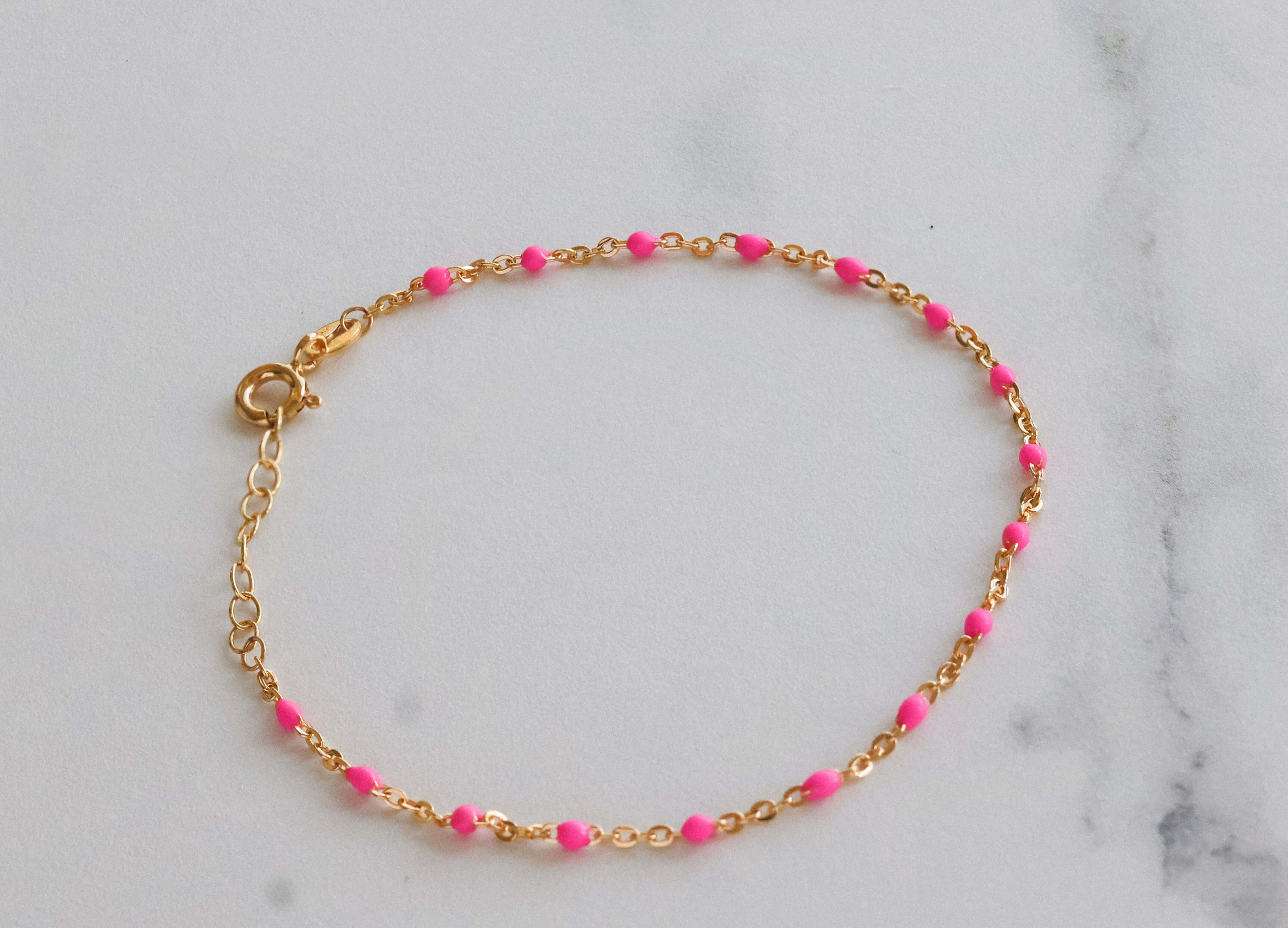 14k gold pink beaded bracelet on a marble surface, showcasing a delicate design with blush pink beads and gold accents.
