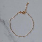 Silver Beaded 14k Gold Satellite Bracelet on marble background, adjustable for comfort and style.