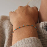 Close-up of a woman's wrist wearing a 14k Gold-Filled Turquoise Beaded Bracelet with delicate gold details.