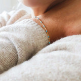 Close-up of a person wearing a 14k gold-filled turquoise beaded bracelet on a cozy sweater.