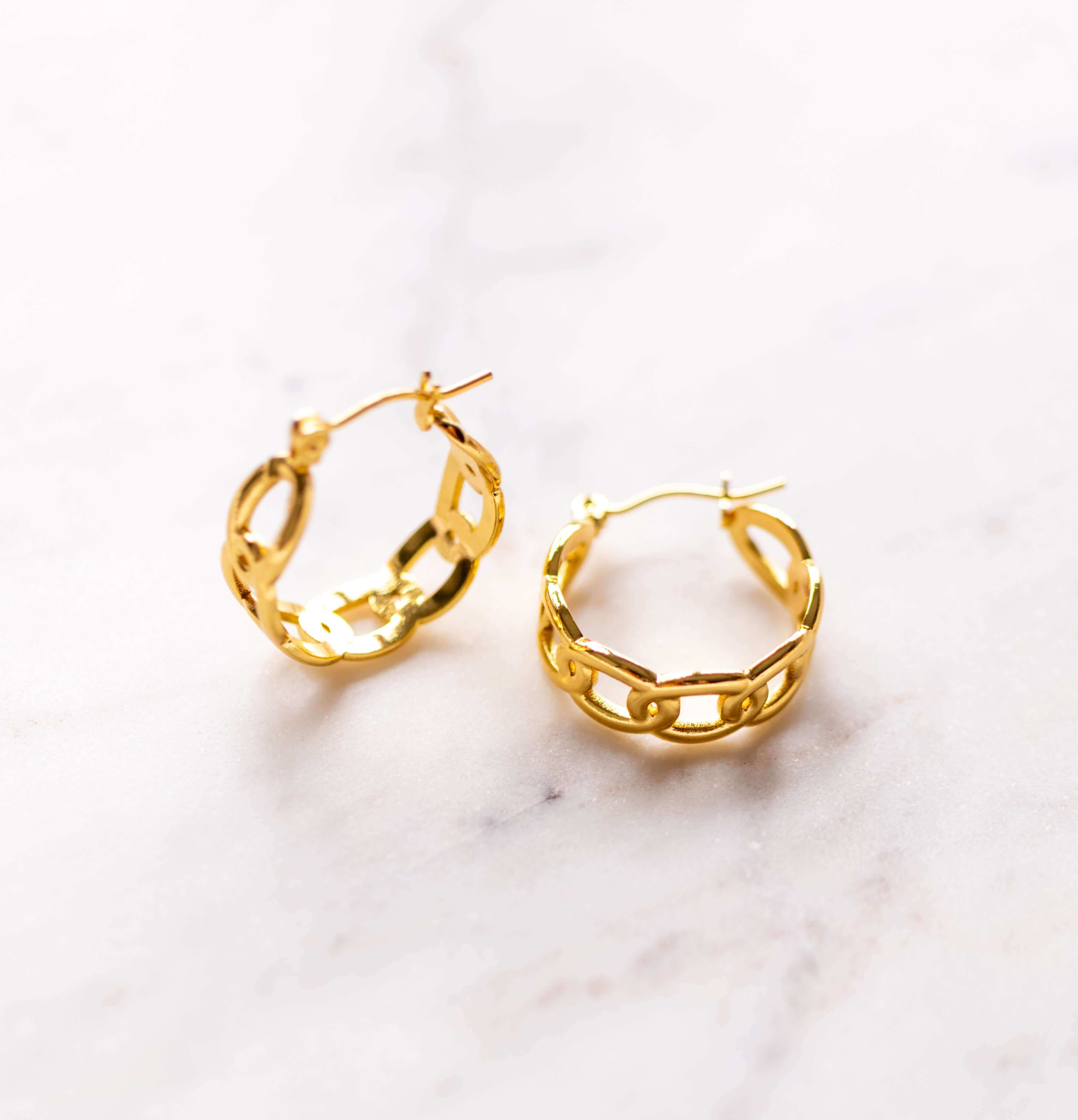 Gold hoop earrings on a light marble background
