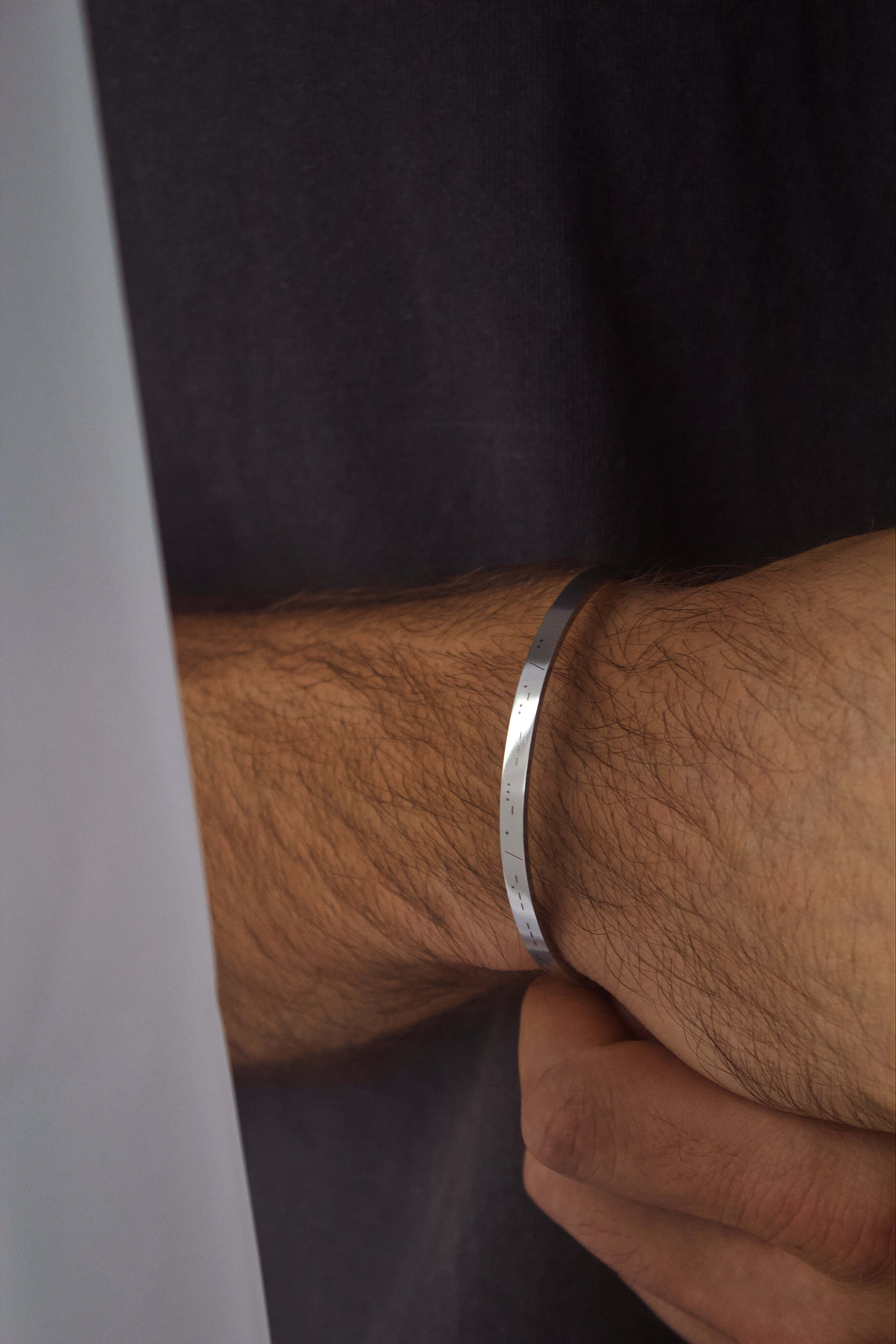 Stylish silver personalised cuff bracelet worn on a man's wrist, featuring custom engraving for added meaning.