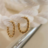 Twisted gold hoop earrings displayed on a textured background, perfect for stylish accessorizing.