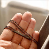 Black personalised bar necklace held in hand, showcasing unique engraving and elegant design.
