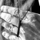Close-up of a hand holding a black personalised bar necklace, showcasing its elegance and engraved design.