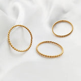 Gold twisted stacking rings on soft fabric background, showcasing their elegant design and luxurious appeal.