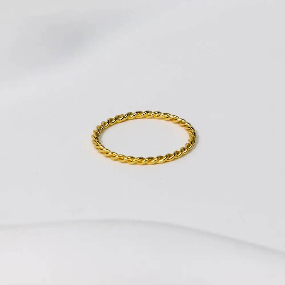 Gold Twisted Stacking Ring on a soft surface, showcasing its artisan design and shimmering finish.