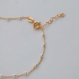 Close-up of the clasp and chain detail on a 14k Gold Satellite Bracelet with Sterling Silver beads.