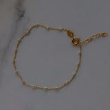 14k Gold Satellite Bracelet with Sterling Silver Beads on marble surface, handmade and adjustable for a perfect fit.