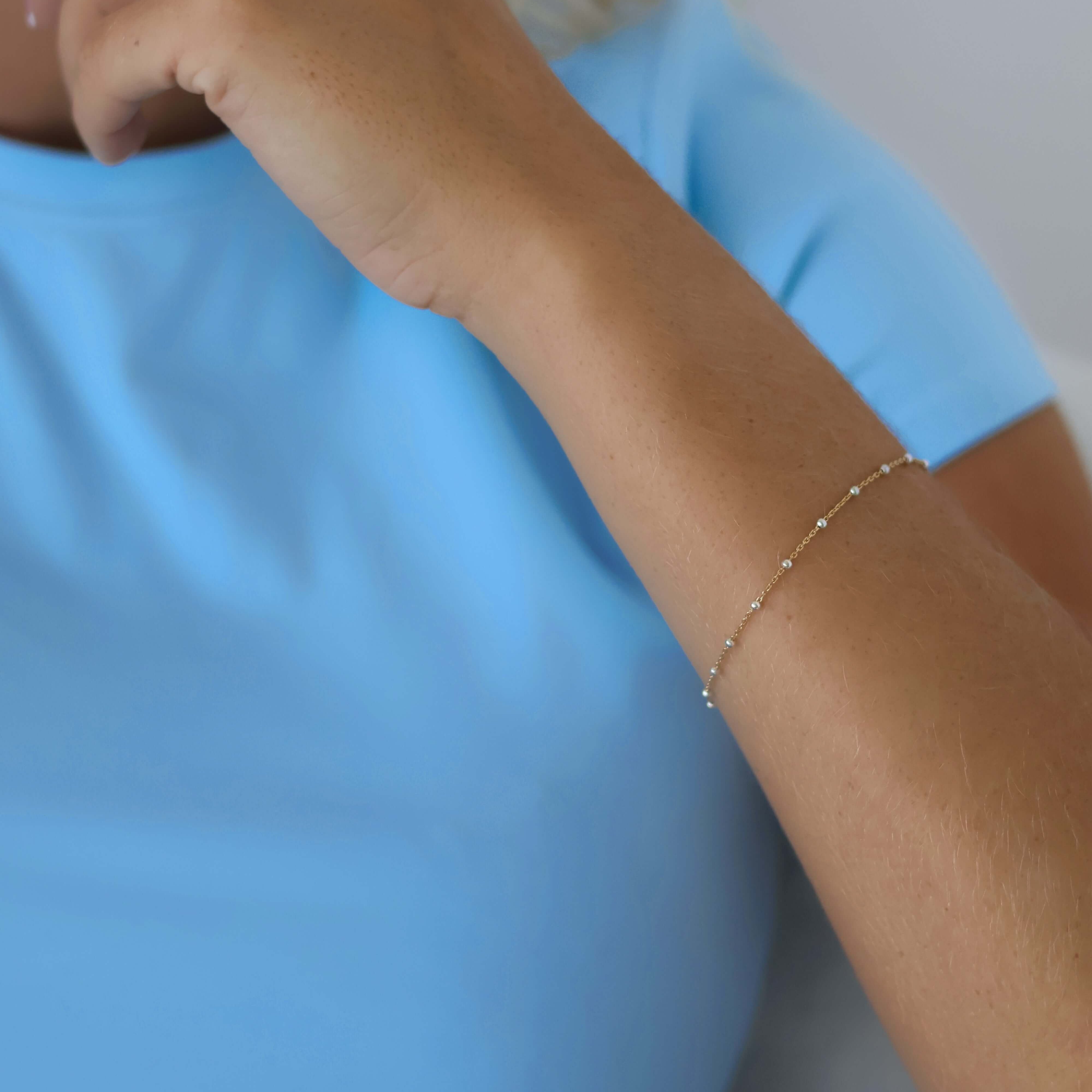 Silver Beaded 14k Gold Satellite Bracelet worn on a woman's wrist with a blue top, showcasing mixed metal elegance.