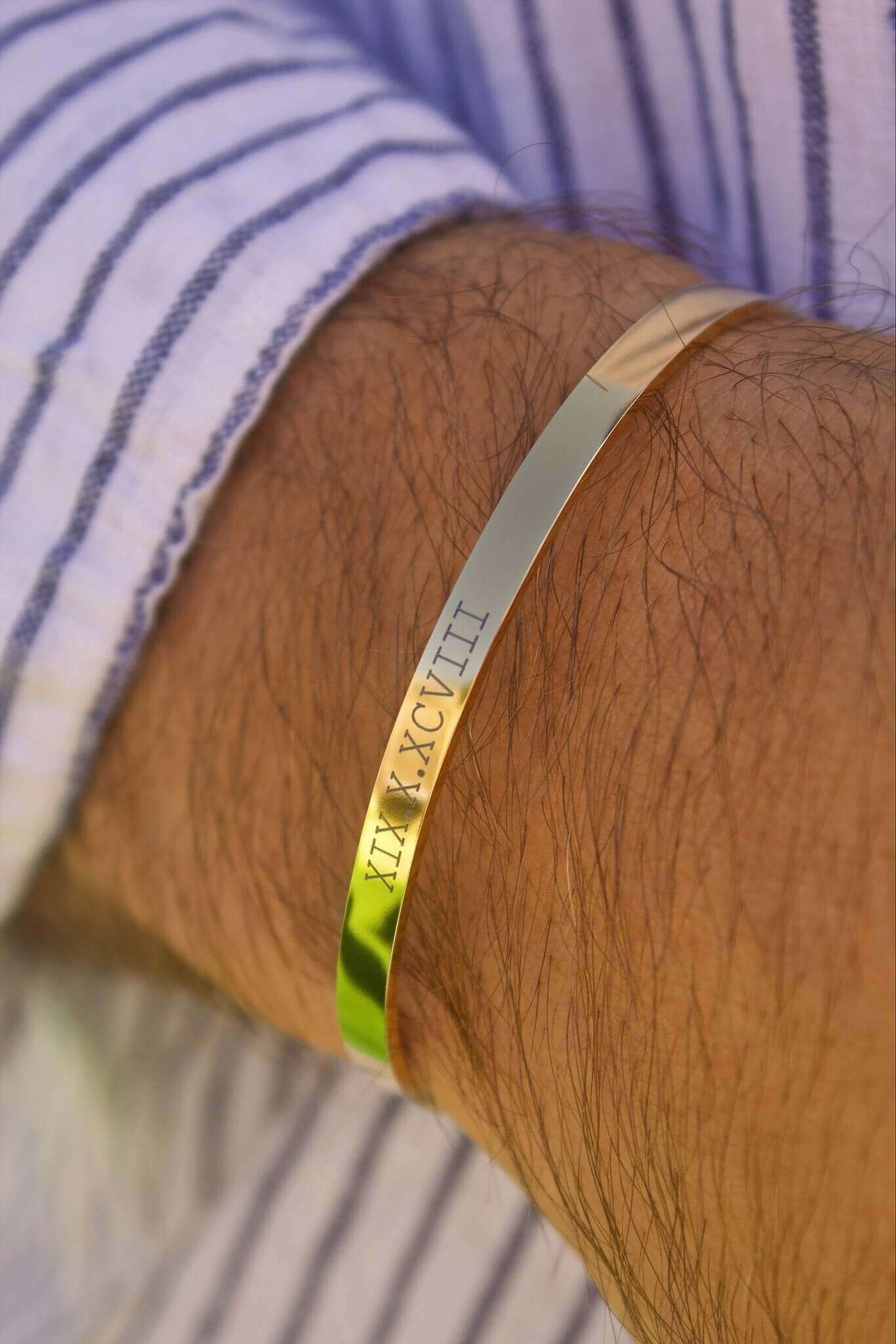 Elegant gold cuff bracelet worn on a wrist, featuring engraved Roman numerals, perfect for stylish accessorizing.