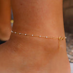 Gold anklet on a person's ankle with a blurred background