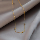 14K Gold Chunky Bead Necklace resting on soft gray fabric, showcasing its elegant design and quality craftsmanship.