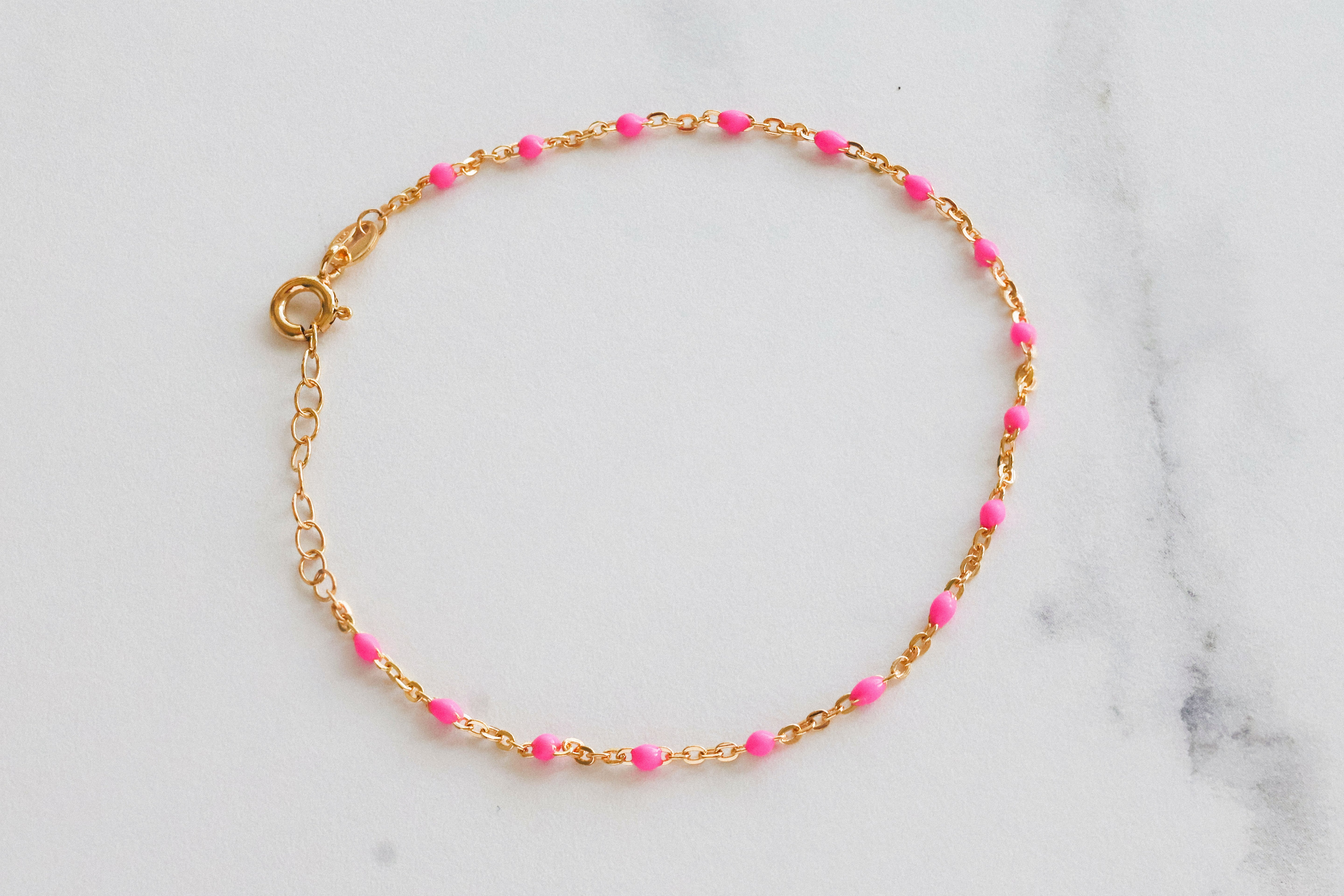 14k gold-filled pink beaded bracelet on marble background, showcasing delicate blush pink beads and adjustable chain design.