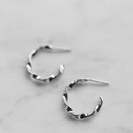 Pair of silver hoop earrings on a light gray background