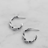 Pair of silver hoop earrings on a light gray background
