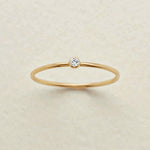 Gold ring with a small diamond on a beige background