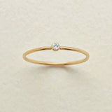 Gold ring with a small diamond on a beige background