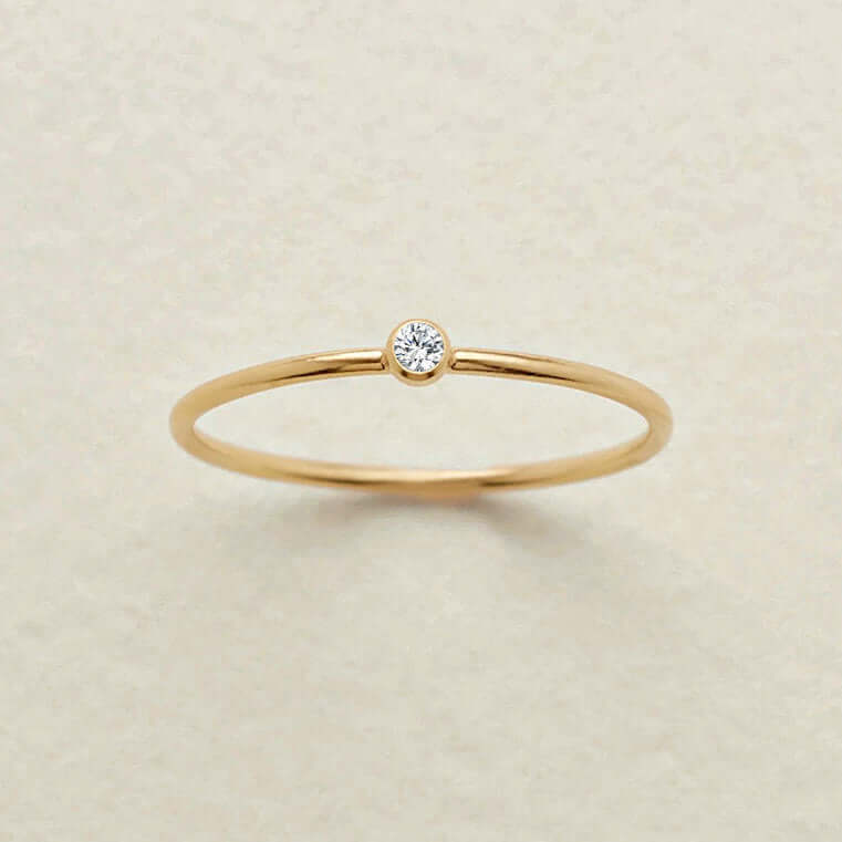 Gold ring with a small diamond on a beige background