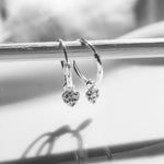 Silver hoop earrings with heart-shaped charms on a white background
