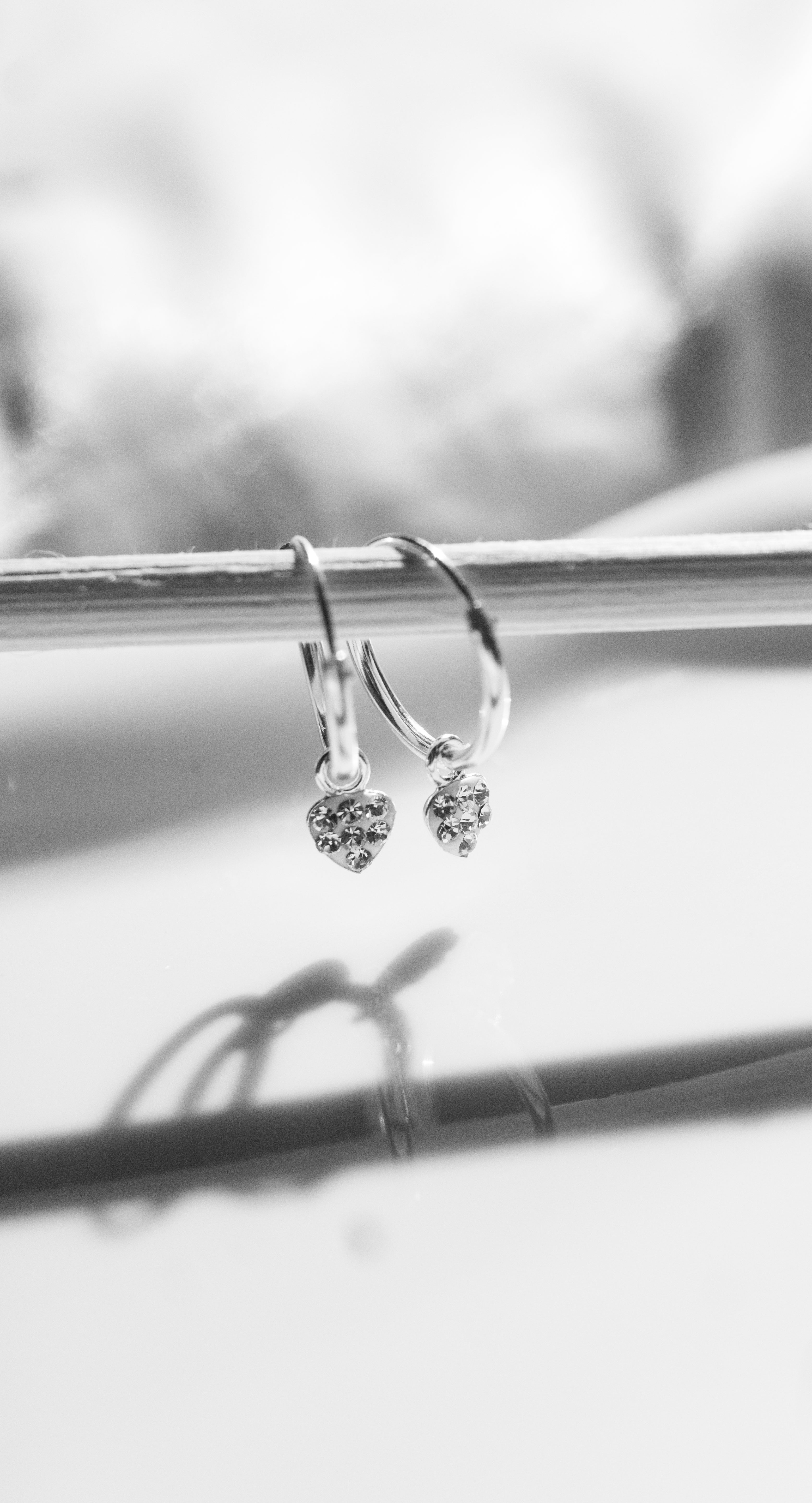 Silver hoop earrings with heart-shaped charms on a white background