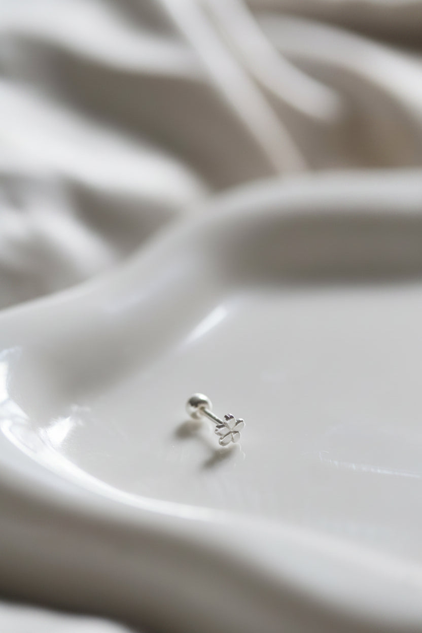 Silver earring on a white ceramic dish