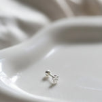 Silver earring on a white ceramic dish