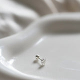 Silver earring on a white ceramic dish