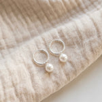Pair of pearl earrings on beige fabric