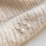 Pair of pearl earrings on beige fabric