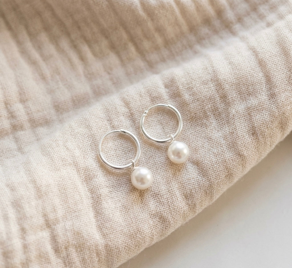 Pair of pearl earrings on beige fabric