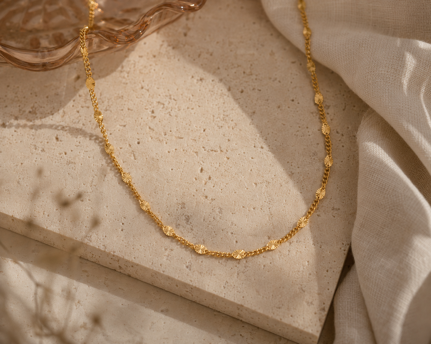 Gold necklace on a textured beige surface