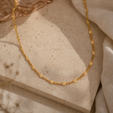 Gold necklace on a textured beige surface