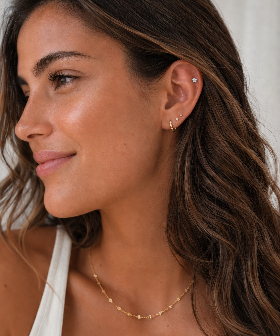 Close-up of a woman wearing earrings and a necklace with a neutral background
