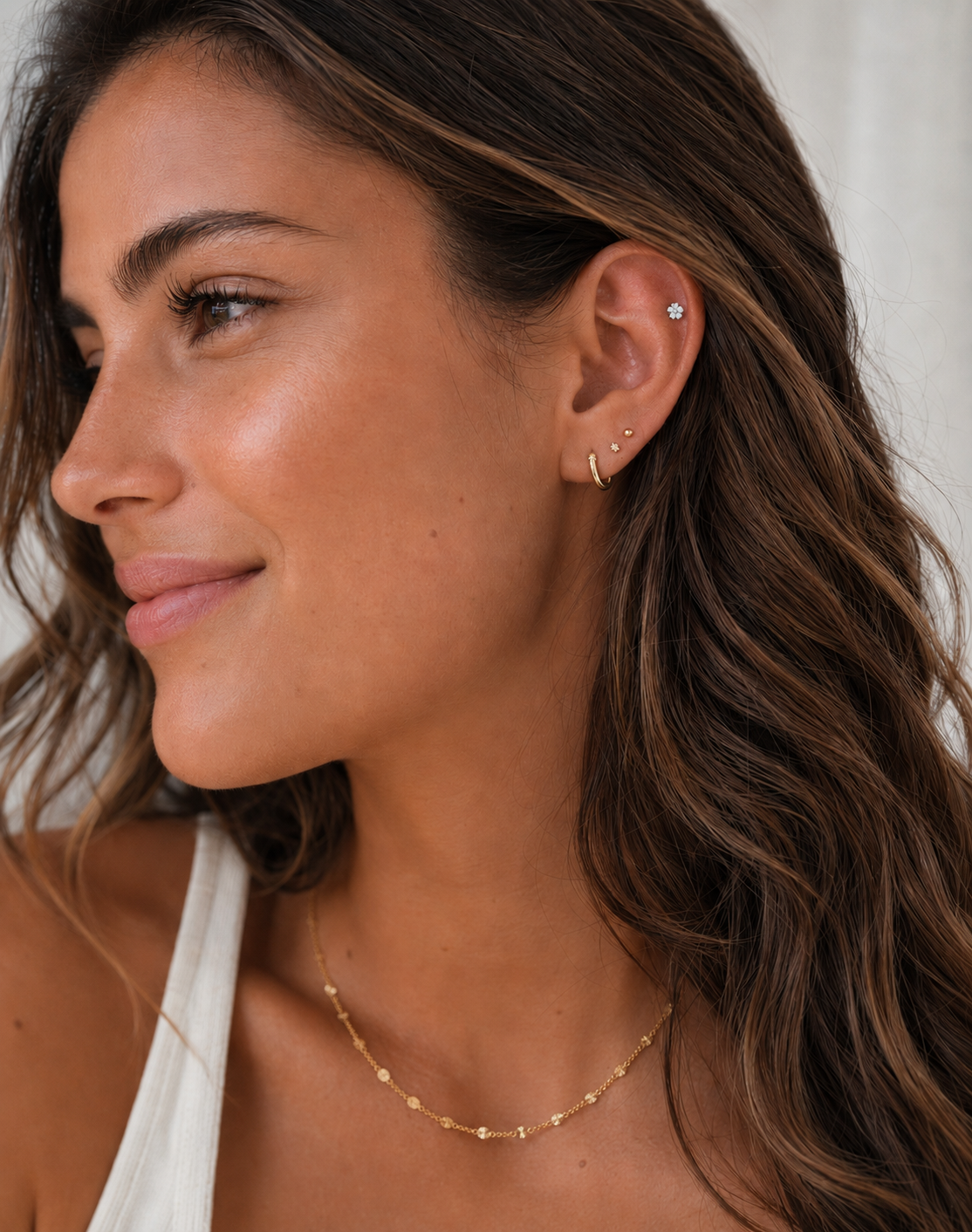 Close-up of a woman wearing earrings and a necklace with a neutral background