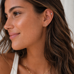 Close-up of a woman wearing earrings and a necklace with a neutral background
