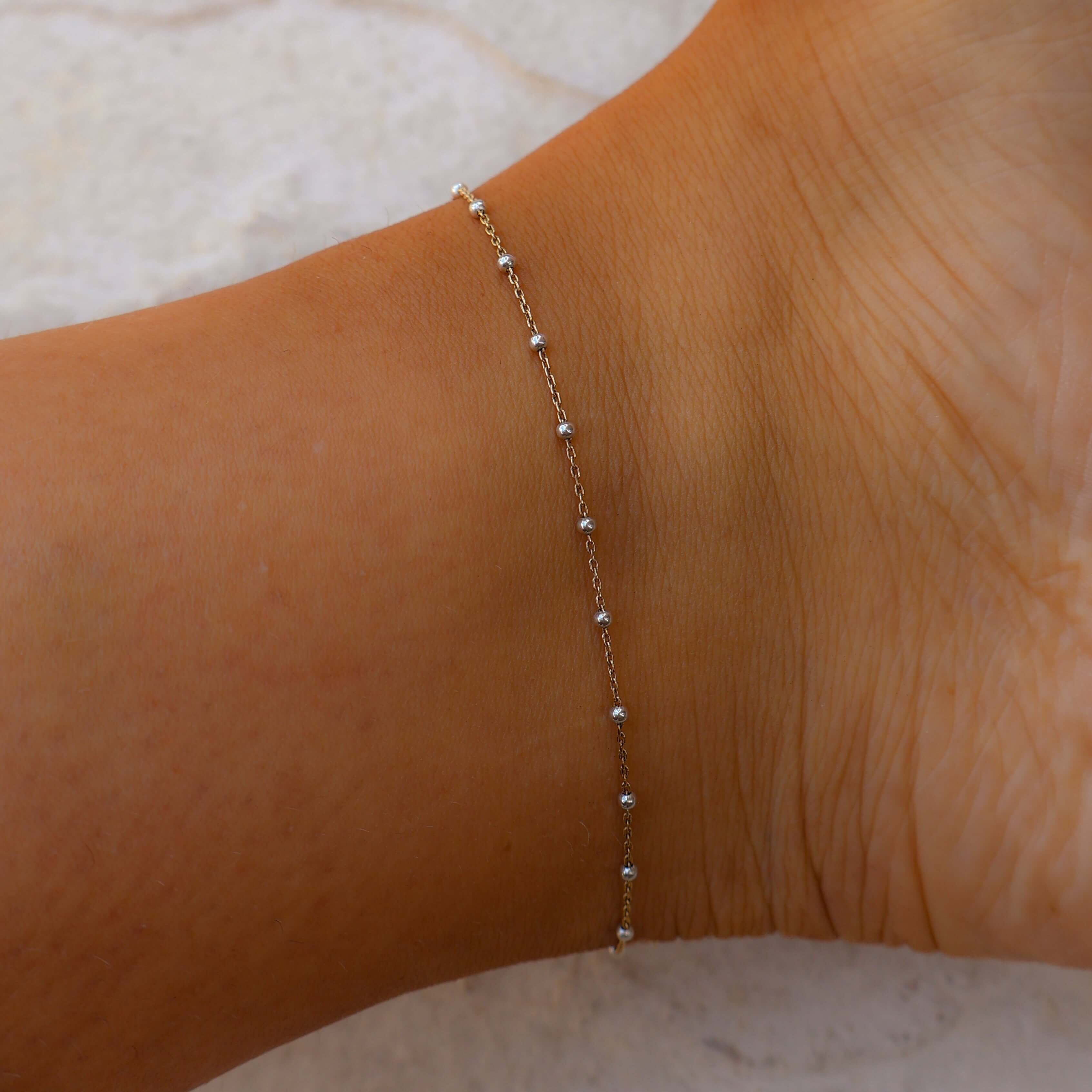 Gold anklet on a person's ankle against a light background