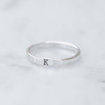 Silver ring with letter 'K' on a light gray background