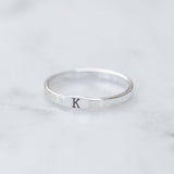 Silver ring with letter 'K' on a light gray background
