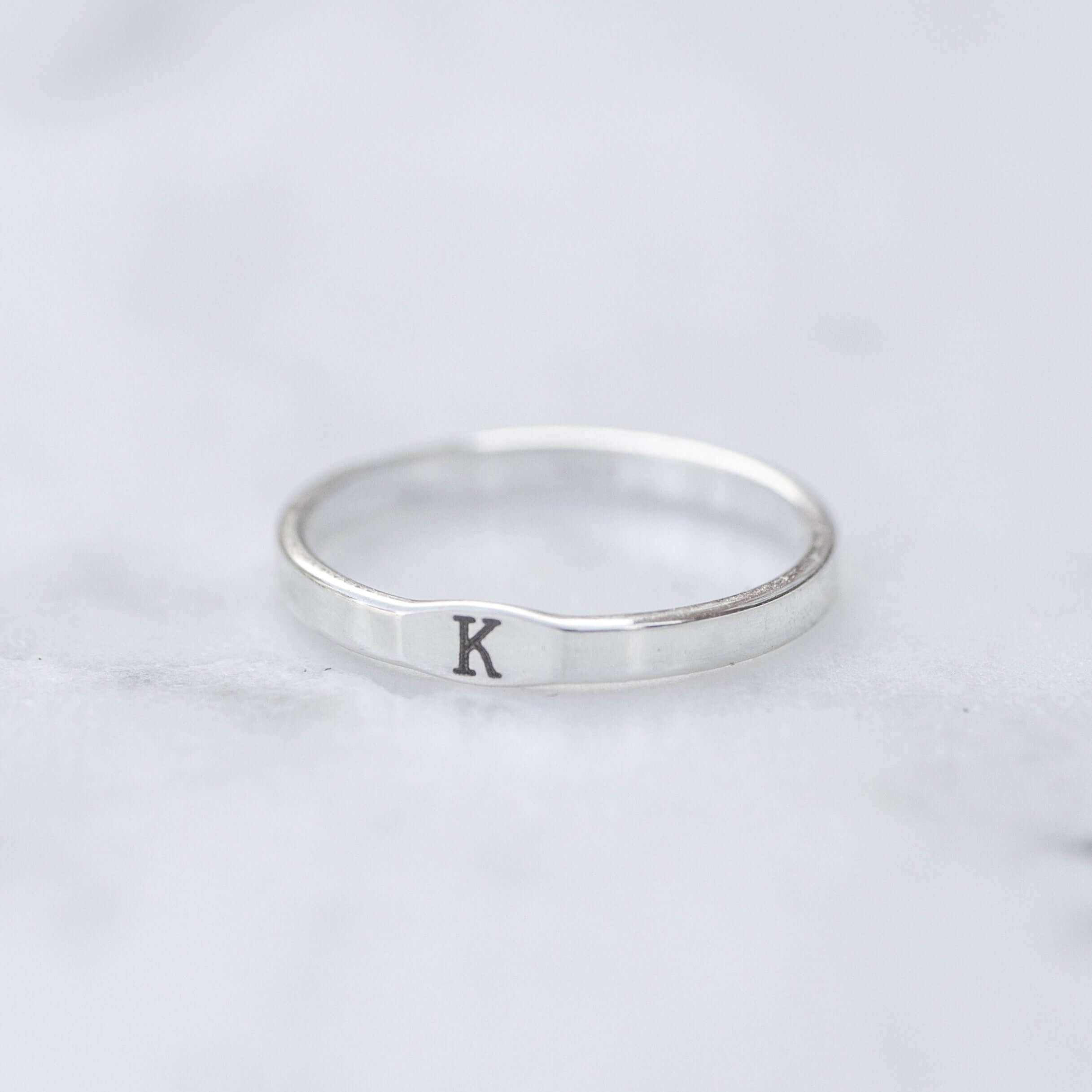Silver ring with letter 'K' on a light gray background