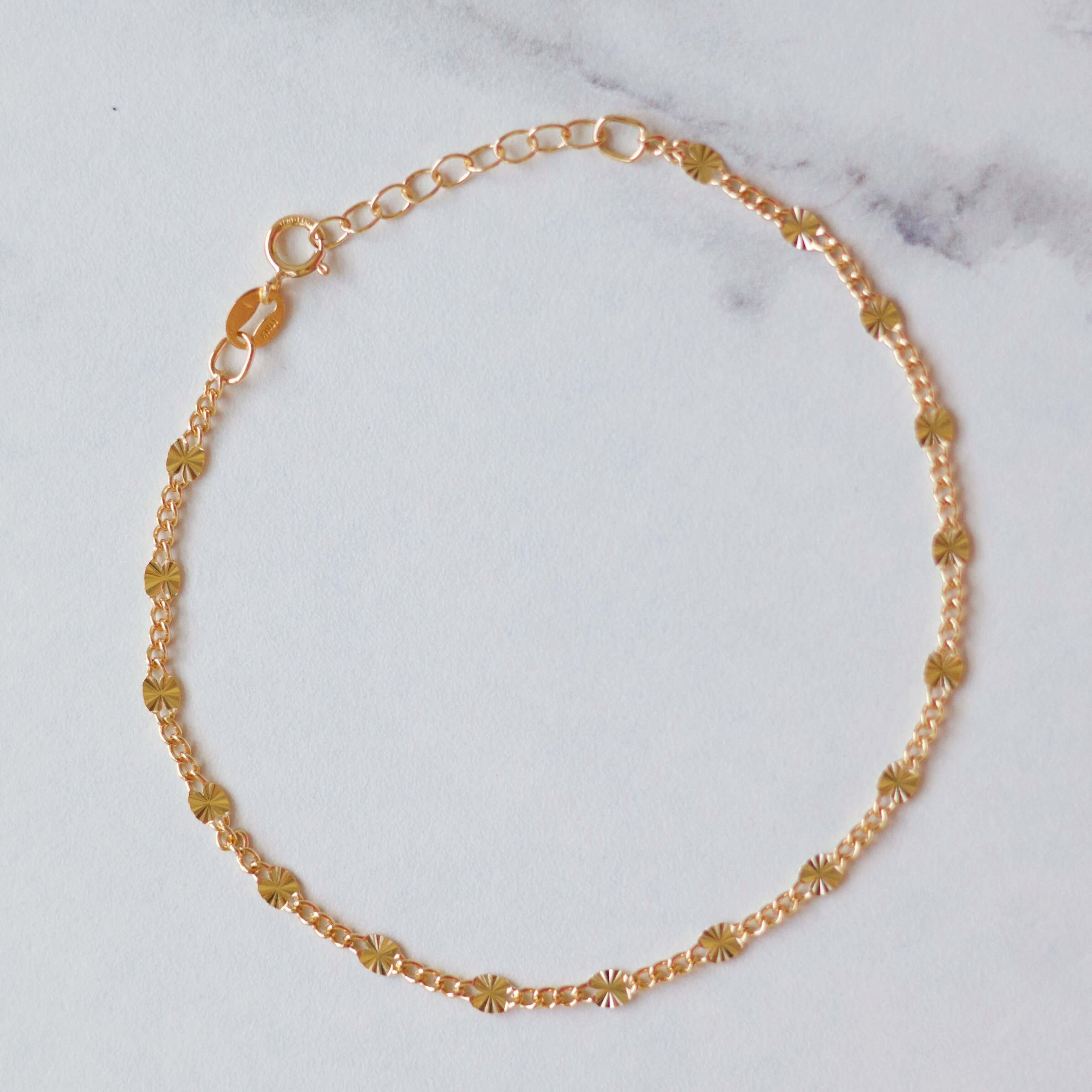 Delicate gold bracelet with sparkling yellow crystals on a light marble background.