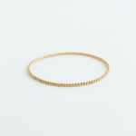 Gold bracelet on a light gray background