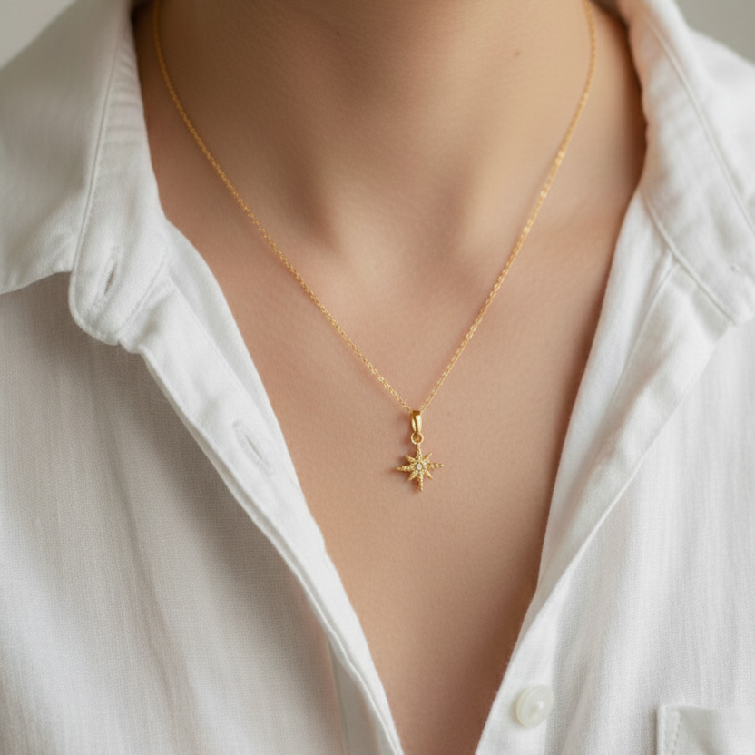Gold necklace with a star pendant worn by a person in a white shirt.
