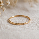 Gold ring on a textured beige surface with dried flowers