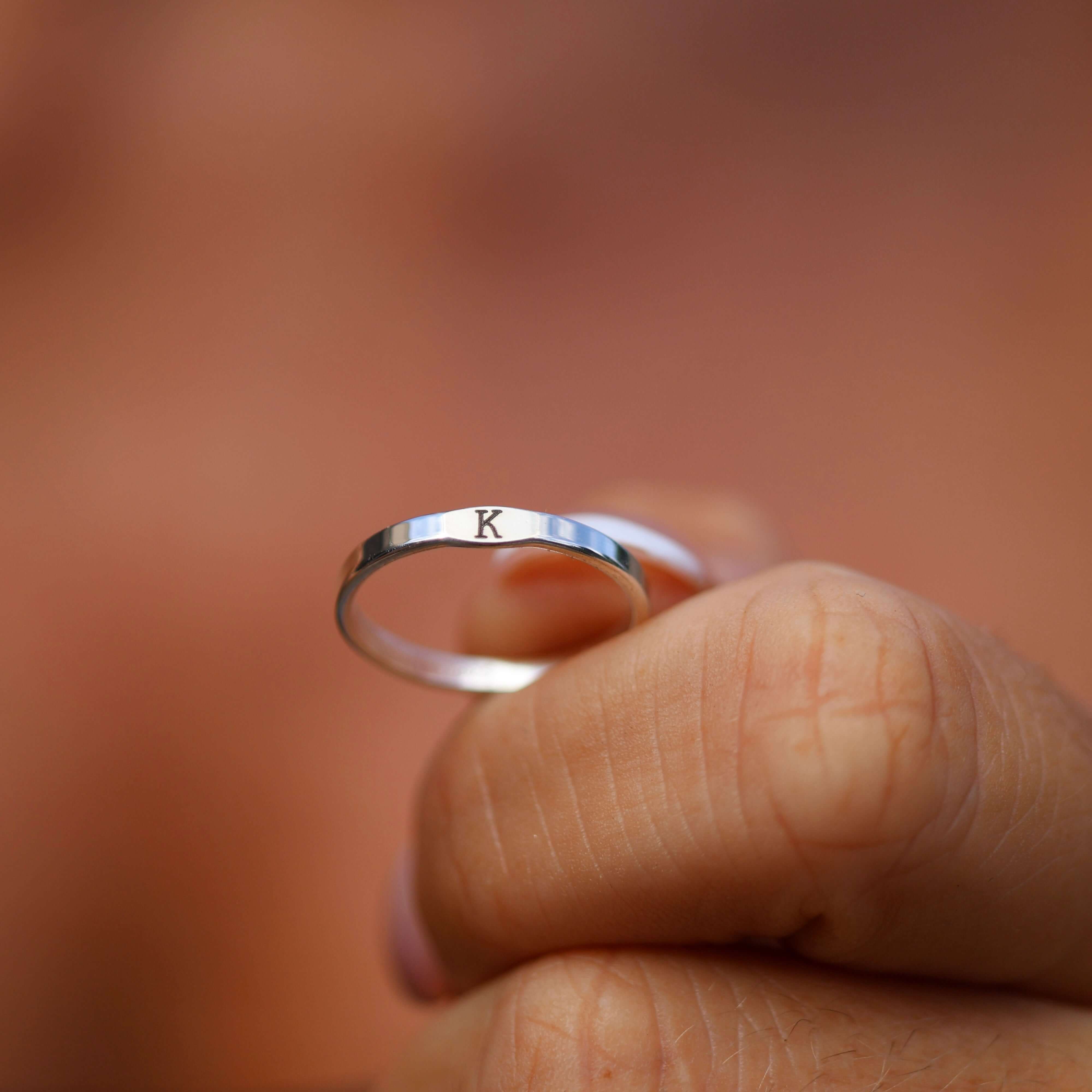 Silver ring with 'K' on a blurred background