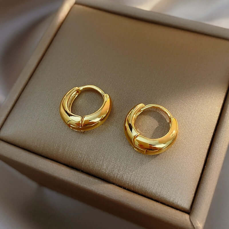 Gold oval hoop earrings displayed elegantly, showcasing their high-quality stainless steel craftsmanship.