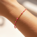 Pink beaded bracelet on womans arm in front of a blurred background