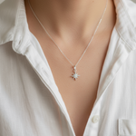 Person wearing a silver necklace with a star pendant against a neutral background