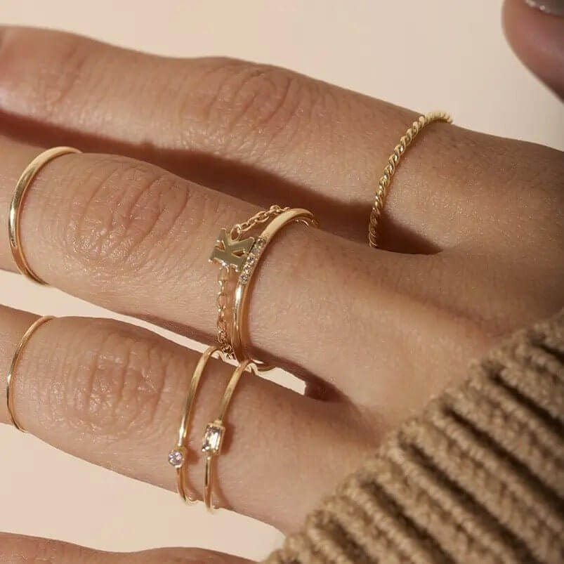 Close-up of a hand wearing multiple gold twisted stacking rings, showcasing elegant handcrafted jewelry style.
