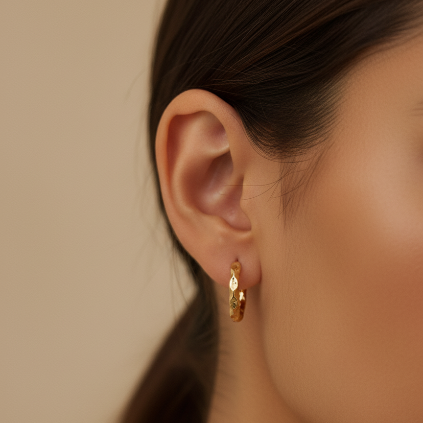 Gold hoop earrings worn by a model against a neutral background